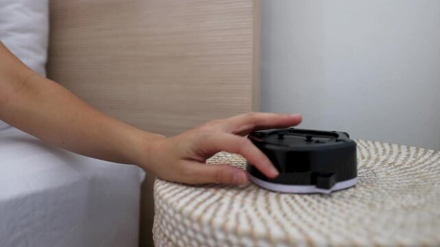 Hand Reaching to Turn Off Alarm Clock on Bedside Table