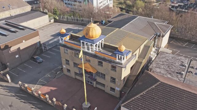 Sikh temple Gurdwara Guru Nanak Gurdwara in Huddersfield Kirklees West Yorkshire England United Kingdom with golden domes and Nishan Sahib flag, drone establishing shot