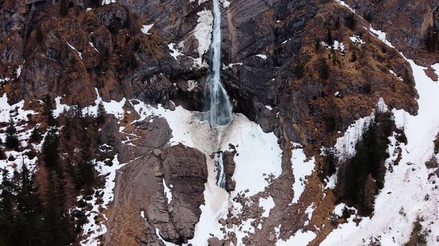 Aerial: Engstligen Falls with snow during the day near Adelboden, second highest fall in Switzerland, establishing drone shot