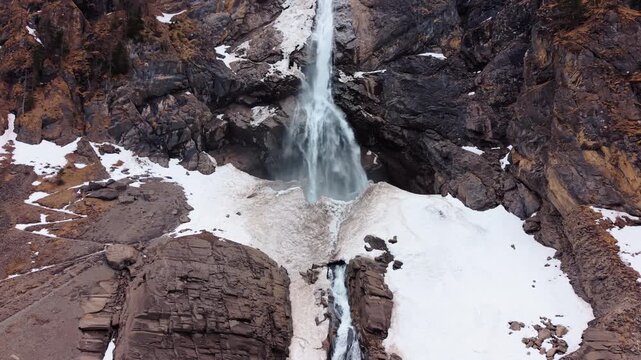 Aerial: close up shot of Engstligen Falls with snow during the day, second highest fall in Switzerland, orbit drone shot