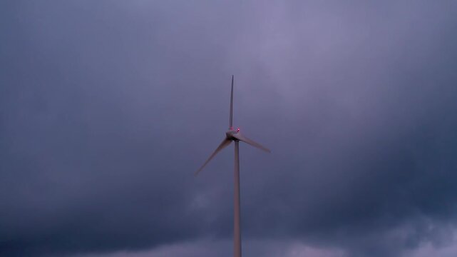 Wind turbine blades actively harnessing wind power, converting natural resources into electricity for a greener future at Serra da Boneca in Portugal, with a dramatic cloudy sky