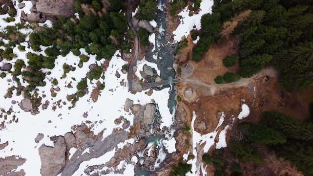 Aerial: river near Engstligen Falls with snow during the day, second highest Swiss waterfall, bird's eye view drone