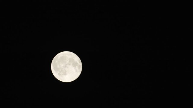 Clear view of the Moon at night against a black sky time lapse ,moving across skyline