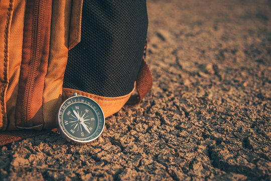 The traveler's compass pointing to the arid land signifies the necessity to find a way out of this drought.