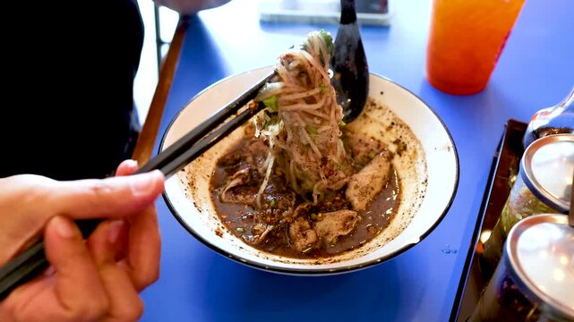 Person Eating Spicy Thai Boat Noodles with Beef and Pork