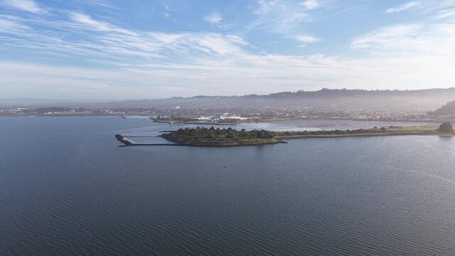 Morning aerial footage capturing the serene landscape of Cesar Chavez Park and Albany Beach in Berkeley, California, with the calm waters of the San Francisco Bay under a partly cloudy sky