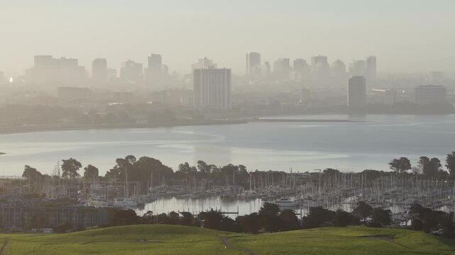 Aerial perspective showing the green hills of Cesar Chavez Park and Berkeley Marina, with the hazy San Francisco skyline emerging from the morning fog across the bay on a beautiful sunrise