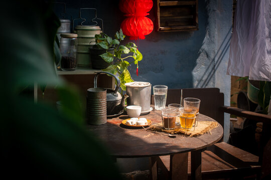 Vintage Southeast Asian coffee set with metal kettle, cloth filter, and glass cups in a rustic cafe atmosphere. Traditional morning beverage concept with nostalgic Thai and Malay cultural vibes.