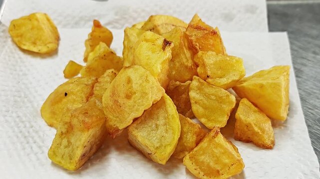 Deep fried potato wedges with crunchy texture on absorbent paper, ready to be served.
