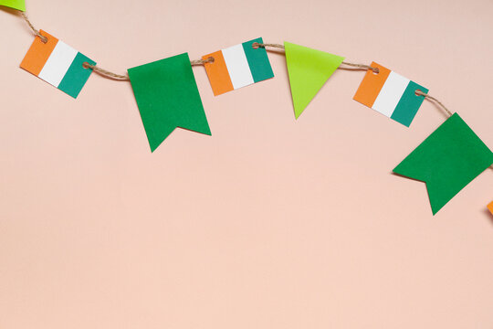 Paper garland with Irish flags for St. Patrick's Day celebration on beige background