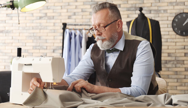 Mature tailor working on sewing machine in atelier