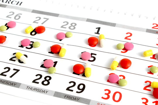 Texture of multi-colored medicine tablets and capsules lie on a white background.
