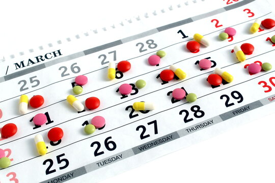 Texture of multi-colored medicine tablets and capsules lie on a white background.