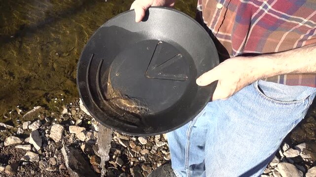 Swirling water in a gold pan and gold collects.