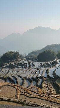 Stunning vertical aerial view of the historic Yuanyang Hani Rice Terraces with water reflections under a cloudy sky in Yunnan province China