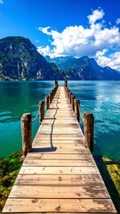 Fototapeta premium A wooden pier extends into vibrant turquoise water towards majestic, craggy mountain ranges under a radiant blue sky with fluffy white clouds