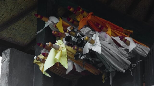 Traditional Balinese Hindu ceremonial umbrellas in white, yellow, and poleng patterns gently moving in the wind. Captures sacred atmosphere, cultural identity, and spiritual elements of temple rituals