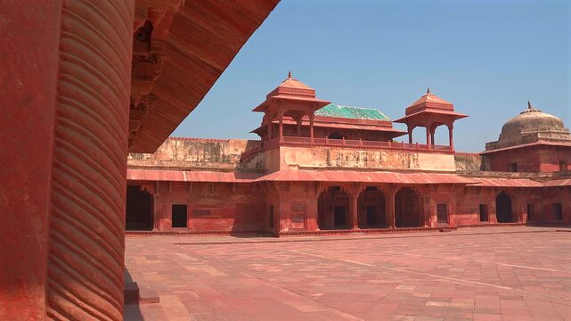 A static shot of the historic red sandstone pavilions and open courtyard within the royal complex of Fatehpur Sikri, showcasing Mughal architectural details.