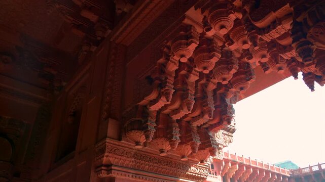 A steady shot capturing the intricate floral inlays and masterful stone carvings on the arches and pillars of Agra Fort, highlighting the refined artistic heritage of the Mughal era.