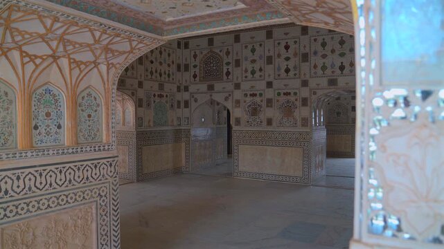 A static wide shot of the interior of the Sheesh Mahal (Mirror Palace) in Amber Fort, showcasing ornate glass mosaics, floral marble carvings, and traditional Rajput palace architecture.