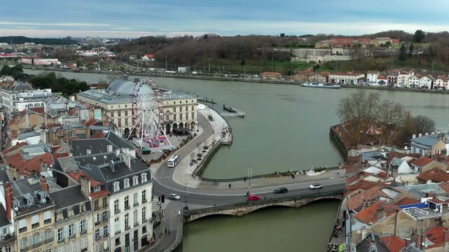 Historic city of Bayonne, Nive river, bridge, town hall, and large Ferris wheel on waterfront, France. Aerial forward