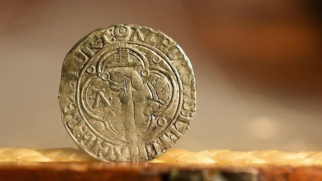 Hand holding a sword on a medieval coin