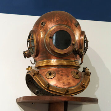 Classic antique copper and bronze diving helmet with multiple fixing bolts.
