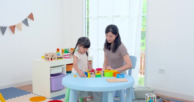 Asian single mother joining preschool daughter with colorful block toys at round table, wide home development scene supporting coordination, sensory play, problem solving, nurturing family bond