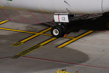 Naklejka premium Close up of an aircraft nose landing gear on tarmac.