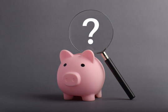 Piggy bank with magnifying glass and question mark. Concept of financial analysis, uncertainty, budgeting, and money planning.