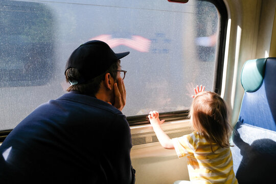Dad and Daughter look out train window during summer trip