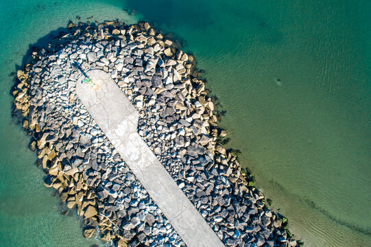 Aerial view of concrete breakwater in blue ocean water