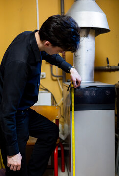 Technician measuring a gas boiler with a tape measure