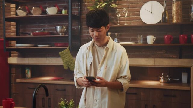 Youthful Asian Selfie, Youthful Asian man casually recording selfie in warm kitchen environment with shelves and clock