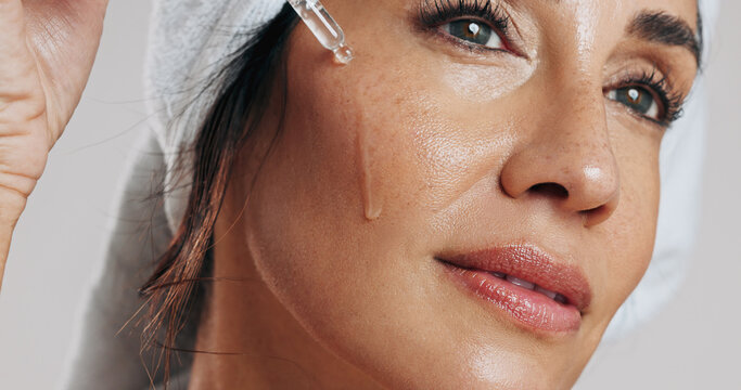 Skincare, thinking or woman with serum in studio, apply hyaluronic acid or anti aging facial treatment. Dropper, dermatology or mature person with product for glowing skin, vision or white background