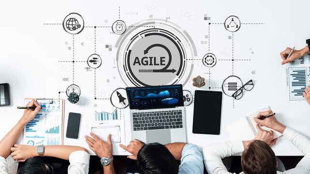A diverse team engages in project management using laptops and digital tools. The workspace displays charts and data, showcasing innovative strategies and collaboration in action. Raster