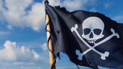 Fototapeta premium Black Pirate Flag with Skull and Crossbones Against a Bright Blue Sky Background