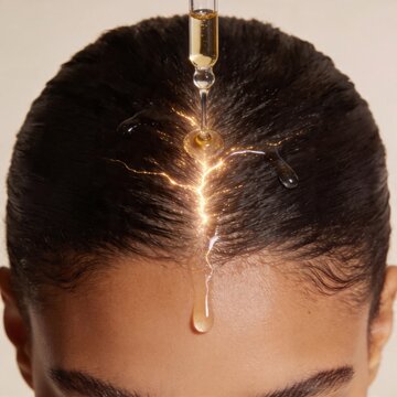 Woman's scalp receiving oil treatment featuring hair serum drops