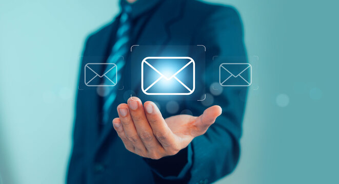 Businessman hand presenting glowing email icon interface, digital communication concept with message notification, contact network, customer support online marketing, futuristic technology connection.