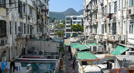 Dense residential apartment buildings with air conditioners and balconies in an urban neighborhood with mountains in the background. © Pierce