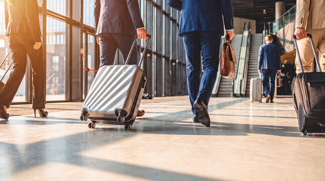 Busy business travelers with luggage walking through a bright modern airport terminal or office lobby.