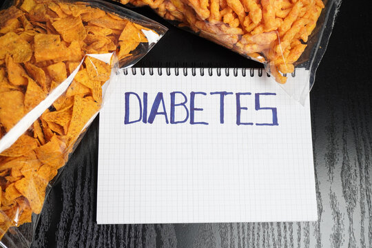 Snacks in a transparent plastic container on a black table. With "Diabetes" Writings in the book page.