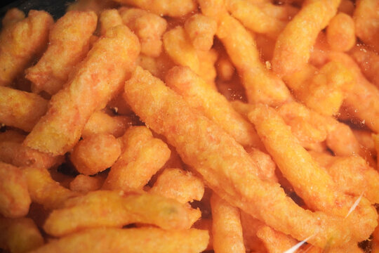 Snacks in a transparent plastic container on a black table. The snacks are classified as ultra-processed food, high in sugar and sodium, making them unhealthy and associated with various diseases.
