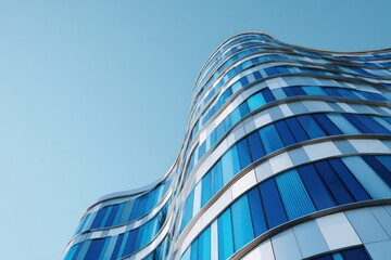 A striking low-angle perspective showcases a modern, curved building with a predominantly blue glass facade against a clear, light blue sky.