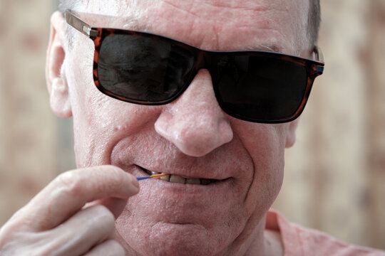 A middle-aged man cleans between his teeth with a dental brush