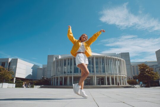 Young woman jumping in front of a modern building