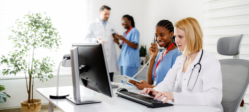 Team of medical workers collaborating at a healthcare office while using technology