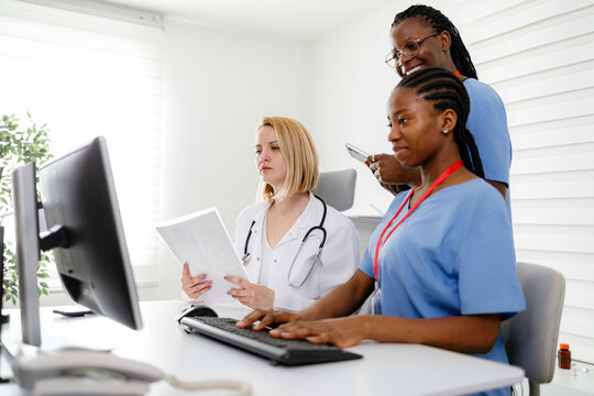 Medical professionals gather around computer to review patient information during work hours
