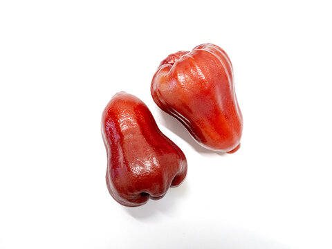 Two red wax apples with glossy skin and water droplets in diagonal composition isolated on white background tropical fruit close up