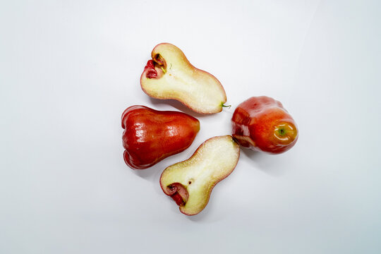 Top view flat lay of red wax apples with whole and sliced pieces arranged in circular composition isolated on white background tropical fruit concept